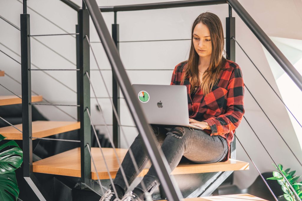 A woman sitting on the stairs and working on a computer