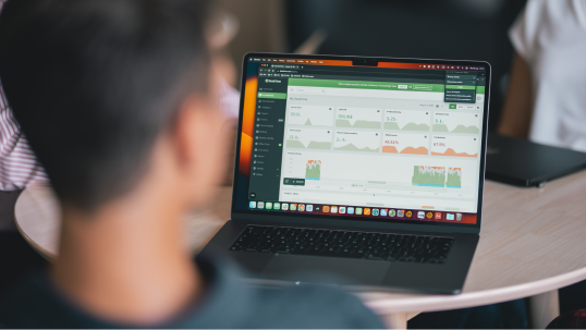 A man looking at the screen of a laptop that has the dashboard of DeskTime time tracker open in a web browser